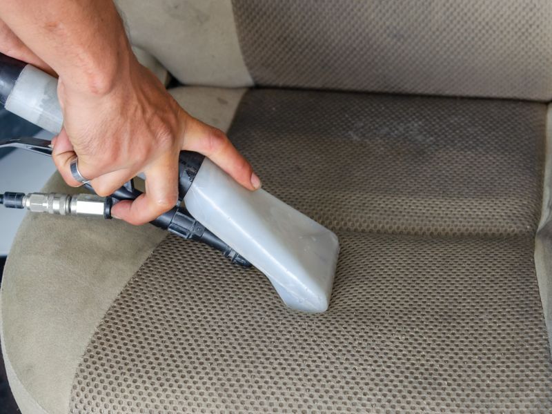 An upholstery extractor drawing dirt out of a fabric car seat.